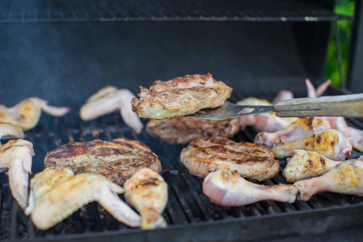 Grilled steak and chiken cooking on an open barbecue